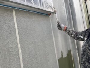 滋賀県大津市にてデザイン事務所兼ご自宅物件の外壁塗装、窓に養生してローラーで下塗り剤を塗布している様子