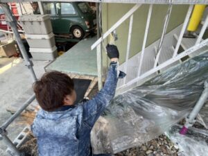 滋賀県大津市で戸建て住宅の鉄骨階段塗装、古い塗膜を剥離させるためのリムーバー剤を職人が刷毛で塗布している様子