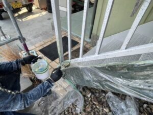 滋賀県大津市で戸建て住宅の鉄骨階段塗装、古い塗膜を剥離させるためのリムーバー剤を職人が刷毛で下から１段目の手摺りの柱に塗布している手元の様子